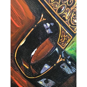 May include: Close-up of a black ceramic mug with gold trim. The mug is partially filled with a brown liquid. The background is a blurred image of a wooden surface.