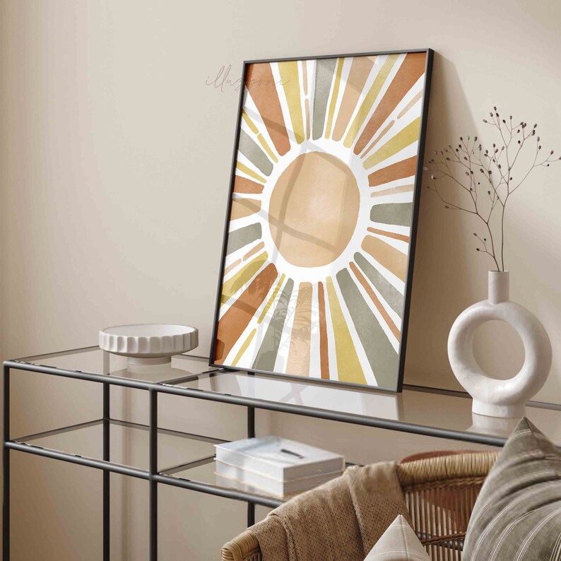 May include: A framed print of a stylized sun with radiating lines in shades of orange, yellow, and green. The sun is a watercolor design with a white background.