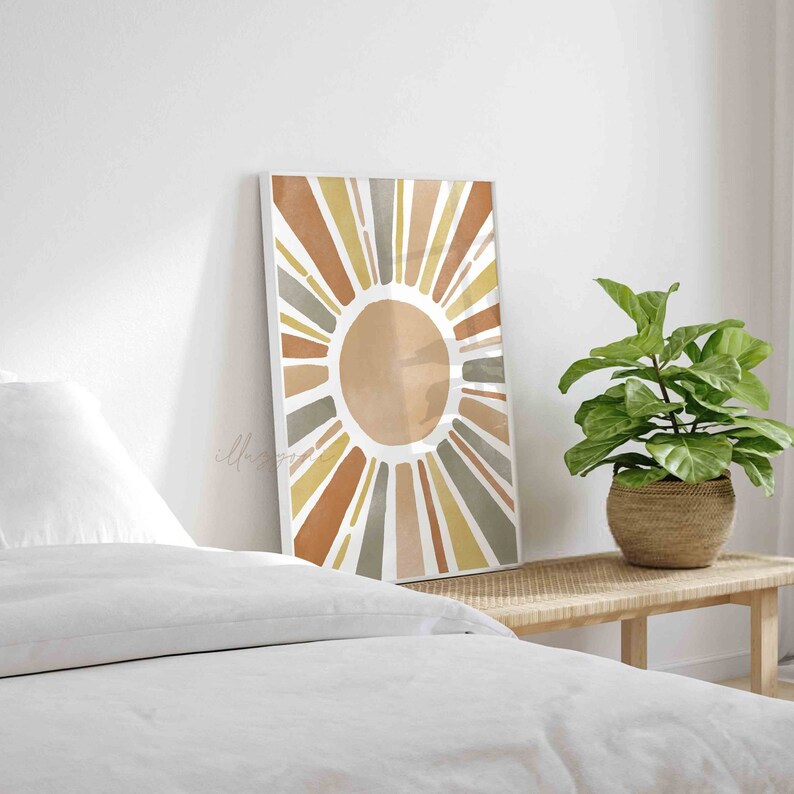 May include: A framed print of a stylized sun with rays in shades of brown, yellow, and gray. The sun is on a white background.