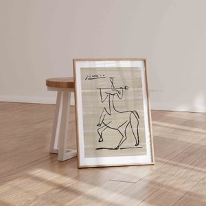 Op de afbeelding: Een ingelijst zwart-wit lijntekening van een persoon die een paard berijdt. De tekening is op een beige achtergrond met een subtiele textuur. De lijst is gemaakt van natuurlijk hout.