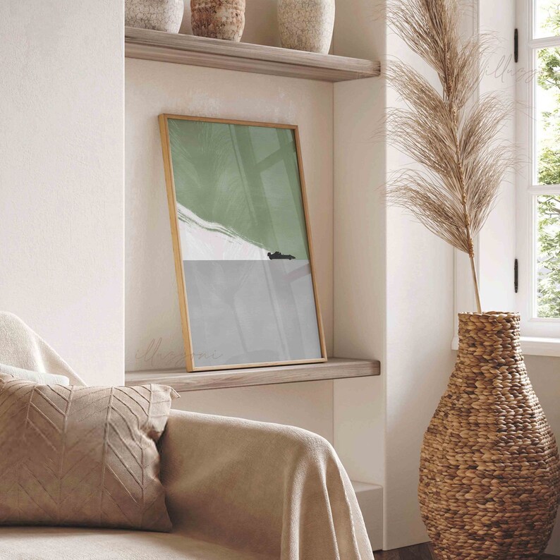 Puede incluir: Una impresi&oacute;n de arte abstracto enmarcada con un esquema de color verde y gris. La impresi&oacute;n est&aacute; colgada en un estante en una habitaci&oacute;n con un sof&aacute; beige y un jarr&oacute;n alto con hierba de la pampa seca.