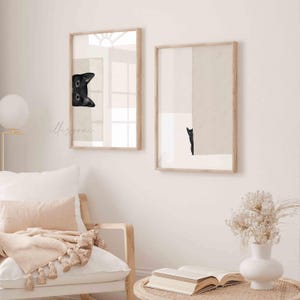 May include: Two framed prints of black cats. The first print shows a black cat peeking around a corner. The second print shows a black cat standing in a doorway.