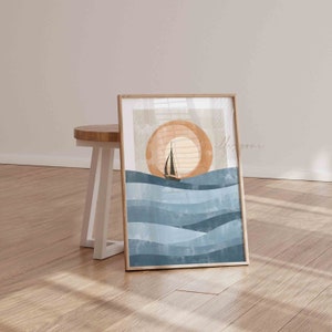 May include: A digital art print featuring a sailboat sailing on blue waves with a large orange sun in the background. The print is framed in a light wood frame.