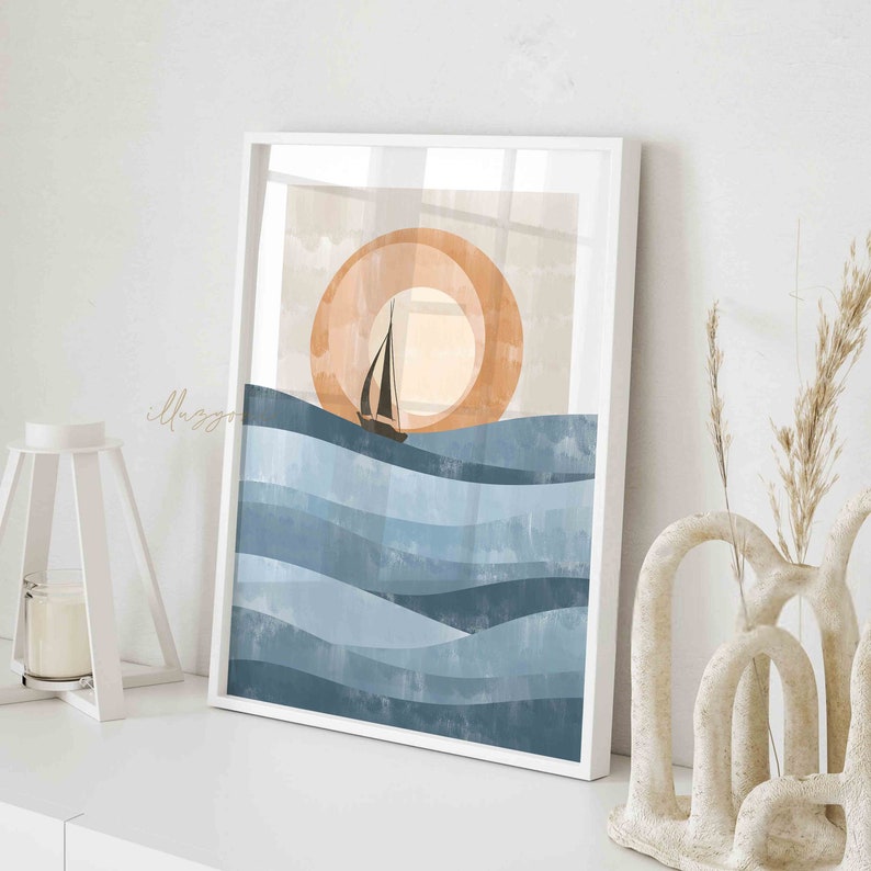 May include: A digital art print featuring a sailboat sailing on blue water waves with a large orange sun in the background. The print is framed in a white frame.