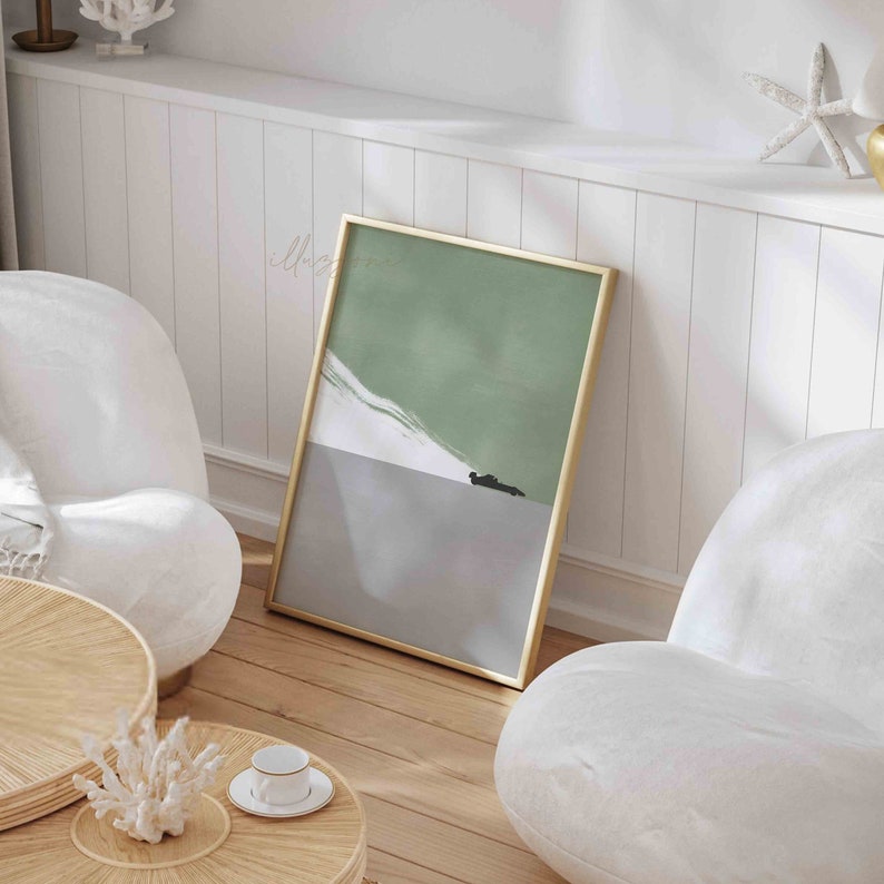 Puede incluir: Una pintura abstracta enmarcada con un esquema de color verde y gris. La pintura est&aacute; colgada en una pared blanca en una habitaci&oacute;n con dos sillas blancas y una mesa de caf&eacute; de madera.