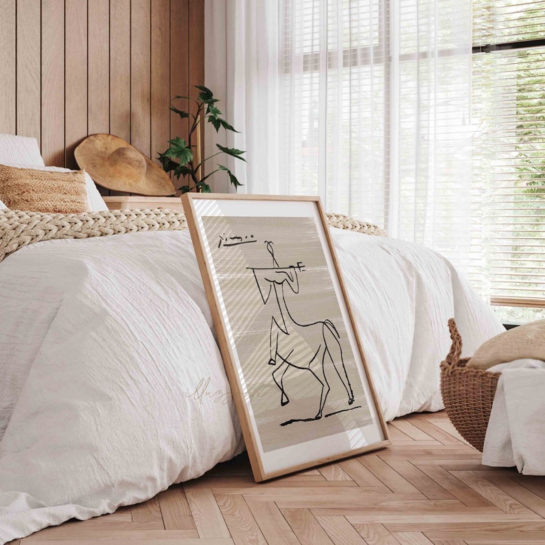 Op de afbeelding: Een ingelijst zwart-wit lijntekening van een persoon die een paard berijdt. De tekening is op een beige achtergrond met een witte rand. De lijst is van hout en heeft een natuurlijke afwerking.