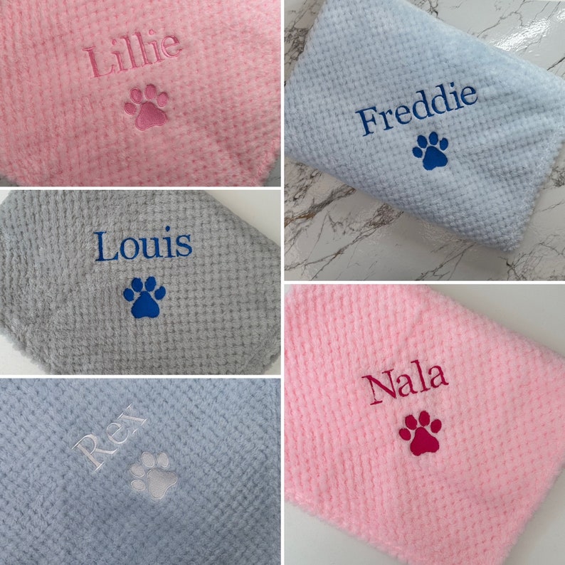 Pode incluir: Uma cole&ccedil;&atilde;o de cinco mantas macias com textura de waffle em rosa, azul claro e cinza. Cada manta apresenta bordados personalizados com os nomes Lillie, Freddie, Louis, Rex e Nala, acompanhados por um &iacute;cone de pata bordado.