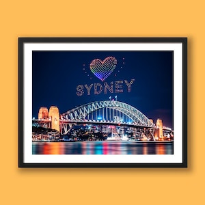 May include: A framed photograph of the Sydney Harbour Bridge at night. The bridge is lit up, and the word "SYDNEY" is spelled out in lights above it, with a heart-shaped display of colourful lights.