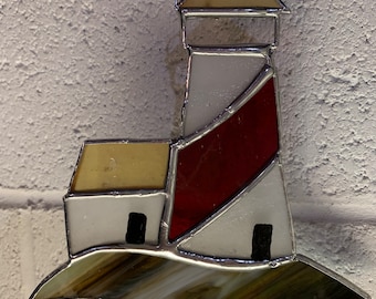 May include: A stained glass lighthouse ornament with a white base, red and yellow accents, and a brown and white glass base.