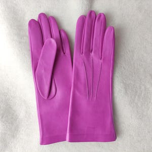 Peut inclure: Une paire de gants magenta vif avec une finition lisse. Les gants pr&eacute;sentent trois lignes de couture verticales sur le dos de la main et un pouce positionn&eacute; sur le c&ocirc;t&eacute;. La conception est &eacute;pur&eacute;e et simple, sans d&eacute;tails superflus.