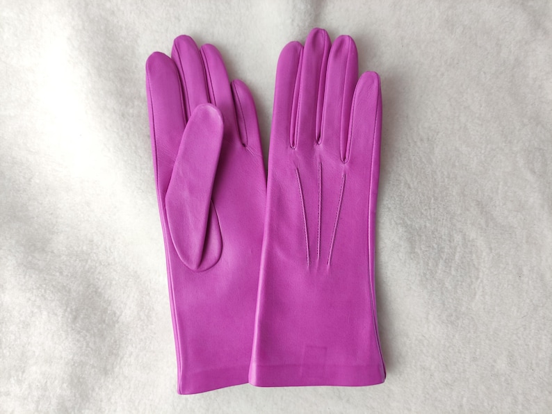 Peut inclure: Une paire de gants magenta vif avec une finition lisse. Les gants pr&eacute;sentent trois lignes de couture verticales sur le dos de la main et un pouce positionn&eacute; sur le c&ocirc;t&eacute;. La conception est &eacute;pur&eacute;e et simple, sans d&eacute;tails superflus.
