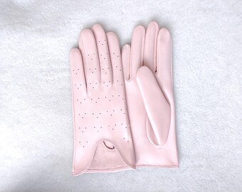May include: A pair of light pink gloves featuring a smooth finish on the palm side and a perforated design on the back of the hand. The gloves have a curved wrist opening with a visible suede-like texture at the cuff and stitched seams.