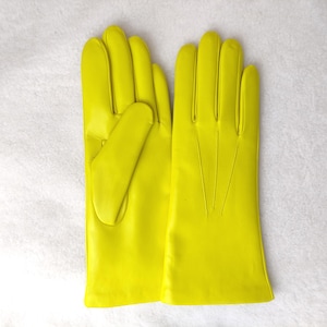 Peut inclure: Une paire de gants jaune n&eacute;on vif avec une finition lisse, quatre doigts et un pouce. Le dos du gant droit pr&eacute;sente trois lignes verticales cousues s'&eacute;tendant de la base des doigts vers la zone du poignet.