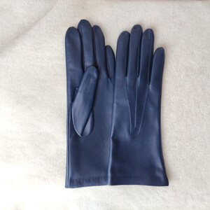 Peut inclure: Une paire de gants en cuir bleu marine avec une finition lisse, quatre doigts et un pouce. Le dos du gant droit pr&eacute;sente trois lignes verticales cousues s'&eacute;tendant du poignet vers les articulations pour plus de d&eacute;tails.