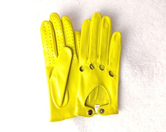 May include: A pair of bright yellow leather gloves featuring perforated detailing along the fingers, knuckle cutouts, and a wrist strap secured with a metal snap button. A small white tag inside the wrist displays the size 6.5.