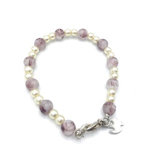 May include: A bracelet with alternating white and purple beads. The bracelet has a silver clasp and a silver charm.