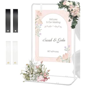 May include: A white metal wedding sign with a floral arrangement and a sign that reads "Welcome to Our Wedding" with the names "Sarah & John" and the date "OCT 25TH.2025". Includes black and white hanging straps.