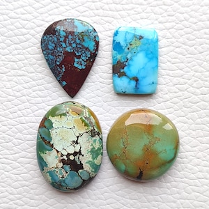 May include: Four polished turquoise gemstones of varying shapes and colours. One is a teardrop shape with dark brown matrix, one is a rectangular bright blue stone, one is an oval with green and white patterns, and one is a round olive green stone.