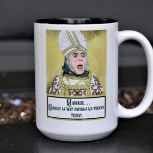 May include: White ceramic coffee mug with a black rim. The mug features a cartoon image of a man in a bishop's robe and mitre. The text on the mug reads "Mawage... Mawage is wat bwings us togeva today."