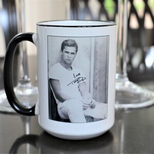 May include: White ceramic mug with a black handle and black rim. The mug features a black and white photo of a man with the text "Love Tony Curtis" printed below the photo.