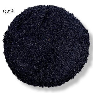 Può includere: Primo piano di un mucchio di polvere nera. La parola "Dust" è scritta in bianco nella parte superiore dell'immagine.