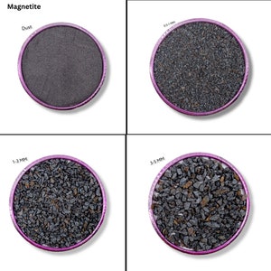 Op de afbeelding: Vier monsters magnetiet in verschillende maten: stof, 0,5-1 mm, 1-3 mm en 3-5 mm. Elk monster bevindt zich in een kleine, ronde, roze schaal.