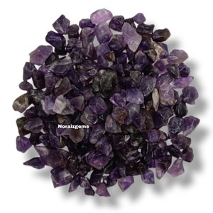 May include: A pile of small, purple amethyst chips. The chips are irregular in shape and have a natural, rough texture.