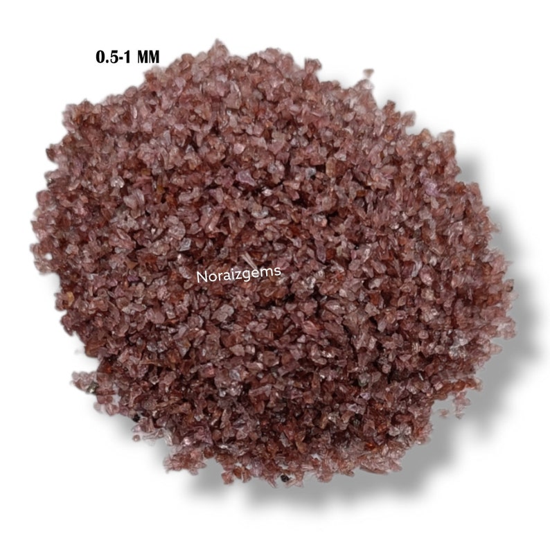 K&ouml;nnte beinhalten: Nahaufnahme eines Haufens kleiner, unregelm&auml;&szlig;ig geformter Edelsteine in rotbrauner Farbe. Die Edelsteine sind etwa 0,5-1 mm gro&szlig;. Der Text "0.5-1 MM" ist in der oberen linken Ecke des Bildes sichtbar.
