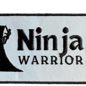 May include: Black and white embroidered patch featuring a silhouette of a person climbing a wall and the text "Ninja Warrior".