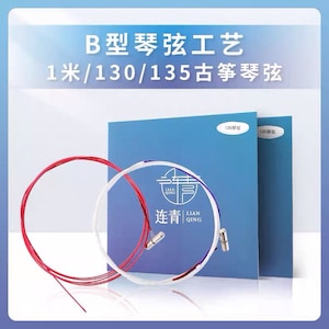 Peut inclure: Deux bobines de cordes pour cithare, l'une rouge et l'autre blanche, sur un fond bleu. Les bobines sont étiquetées "135琴弦" et "连青 Lian Qing".