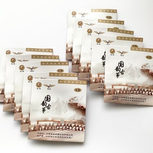 Peut inclure: Une pile de 10 sachets en papier blanc avec un motif brun et or. Les sachets présentent un caractère chinois pour "Guqin" et une image d'un Guqin, un instrument de musique traditionnel chinois. Le texte sur le sachet indique "Guqin Music".