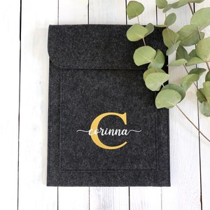 May include: A gray felt laptop sleeve with a gold letter "C" and the name "corinna" embroidered in white.
