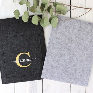 May include: Two felt laptop sleeves, one black with a gold initial "C" and the name "Corinna" embroidered on it, and one gray.