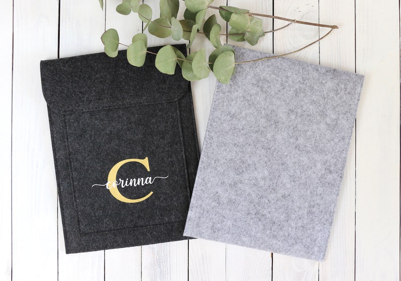 May include: Two felt laptop sleeves, one black with a gold initial "C" and the name "Corinna" embroidered on it, and one gray.