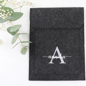 May include: A gray felt laptop sleeve with a white embroidered letter A and the name "annika" underneath.