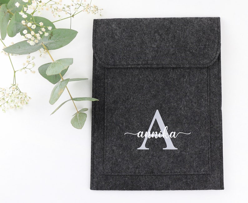 May include: A gray felt laptop sleeve with a white embroidered letter A and the name "annika" underneath.