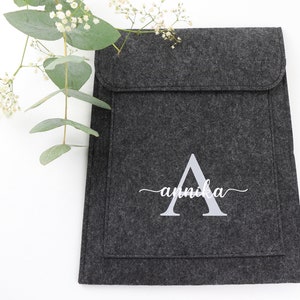 May include: A gray felt laptop sleeve with a white embroidered letter A and the name "annika" in cursive.