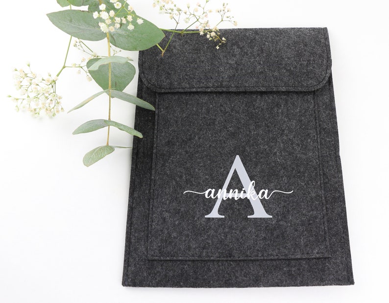 May include: A gray felt laptop sleeve with a white embroidered letter A and the name "annika" in cursive.