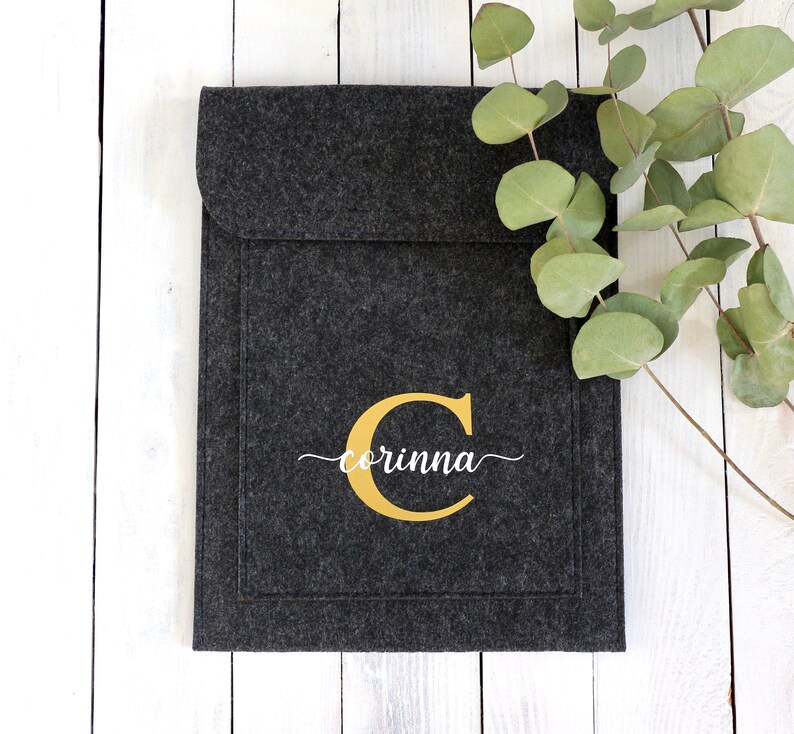 May include: A gray felt laptop sleeve with a gold letter "C" and the name "corinna" embroidered in white.