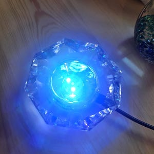 May include: A clear glass base with a blue LED light inside. The base is shaped like a star and has a cord attached to it.