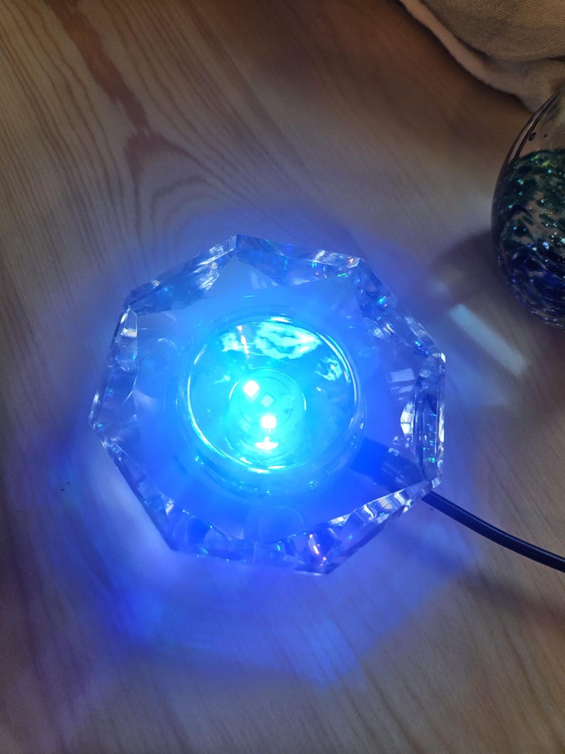 May include: A clear glass base with a blue LED light inside. The base is shaped like a star and has a cord attached to it.