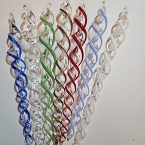 May include: A collection of glass spiral ornaments in various colors, including blue, green, gold, red, and white. Each ornament has a twisted design, creating a decorative effect. These ornaments are ideal for holiday decorations.