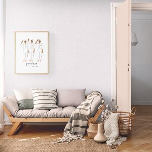 May include: A light-filled room with a wooden framed sofa, throw pillows, and a woven rug. A framed print with the word "goodbye" hangs on the wall. The room has a neutral color palette with a natural, minimalist aesthetic.