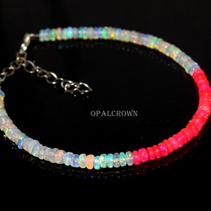 Könnte beinhalten: Ein zartes Armband mit einem Farbverlauf aus bunten Opalperlen. Das Armband wechselt von schillerndem Weiß und Blau zu leuchtendem Pink. Der silberne Kettenverschluss ist verstellbar. Der Text "OPALCROWN" ist sichtbar.