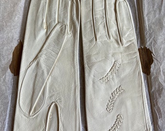May include: A pair of white leather gloves with a stitched leaf design on one glove.