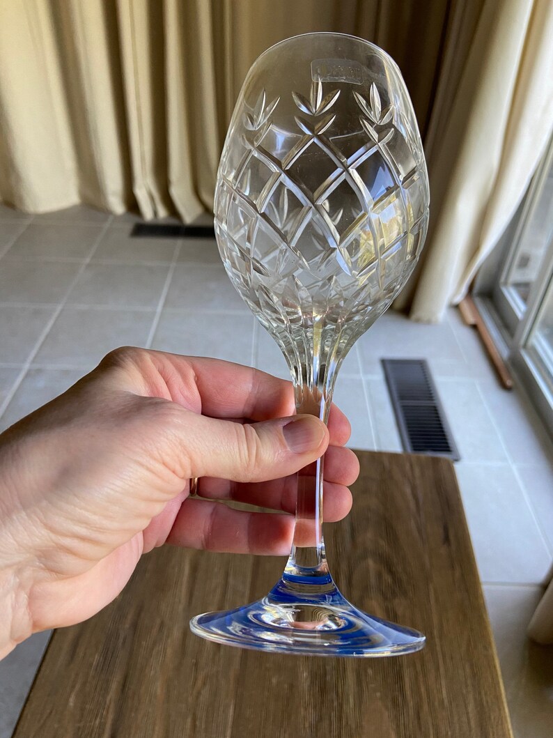 May include: A clear crystal wine glass with a cut diamond pattern. The glass has a blue band around the base.