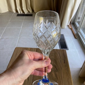May include: A clear crystal wine glass with a diamond pattern and a blue band around the base.