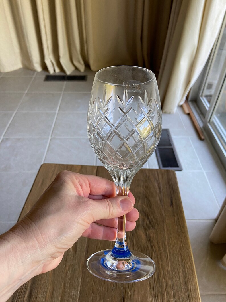 May include: A clear crystal wine glass with a diamond pattern and a blue band around the base.