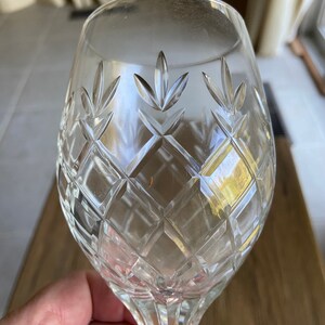 May include: A clear glass wine goblet with a cut crystal design. The goblet has a round bowl and a long stem.