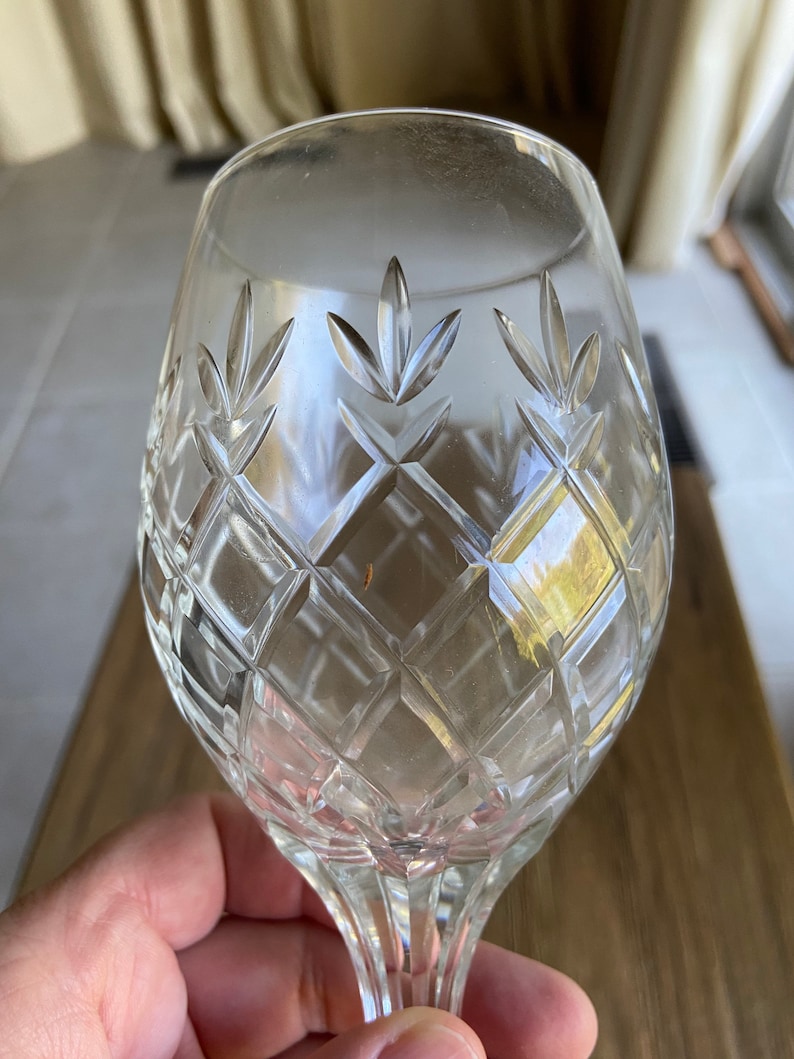 May include: A clear glass wine goblet with a cut crystal design. The goblet has a round bowl and a long stem.